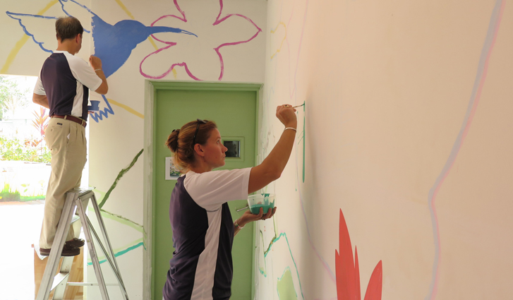 Volunteers help with the painting of floral-themed murals, designed by Singapore artist Adam Wang.