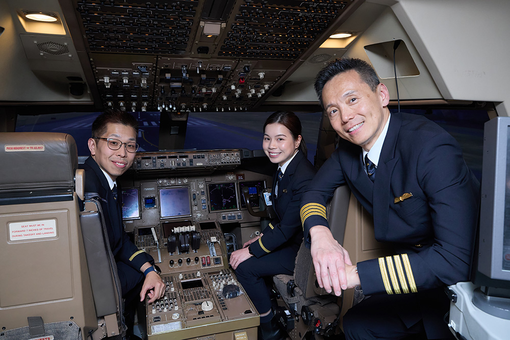 Cadet graduates Tony Yung and Kellie Chiu with Cathay Pacific Training Manager (Pilot Development) Captain Joe Fung in a flight simulator.